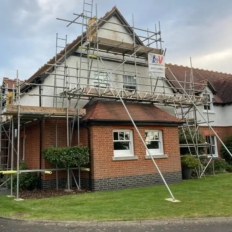 I&V scaffold round the gable and porch of a brick and render house, with the I&V sign on it