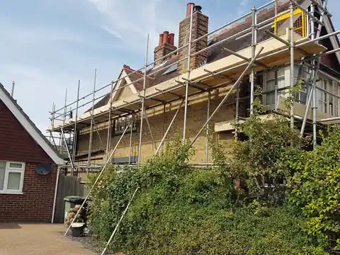 Scaffold along the front and roof of a house with a dormer